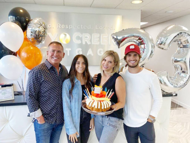 a group of people standing in front of a cake