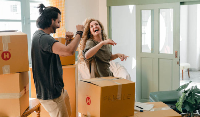 a man and a woman standing in a room with boxes