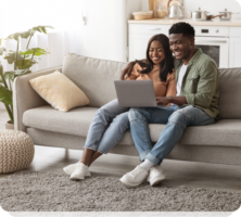 a man and woman sitting on a couch with a laptop
