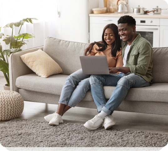 a man and woman sitting on a couch with a laptop